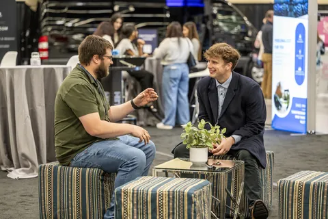 Two attendees talking in a furnished lounge on the Northwest Event Show floor.