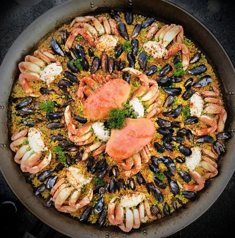Large Paella House seafood paella topped with Dungeness crab and mussels